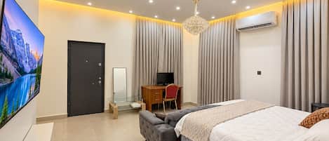 A modern bedroom with a bed, a TV, a desk, and a chair.