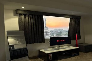 Een moderne woonkamer met een groot raam, een flatscreen televisie en een spiegel.