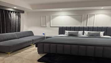 Un dormitorio moderno con una cama grande, un sofá y una mesita de noche.