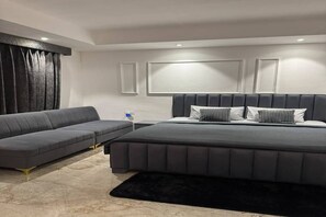 Een moderne slaapkamer met een groot bed, een sofa en een nachtkastje.