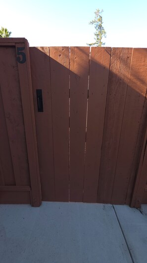 A closed wooden gate with a number '5' on it, a metal latch, and a concrete base. - Private Patio Studio + Desk & TV near SAP Center (San Jose)