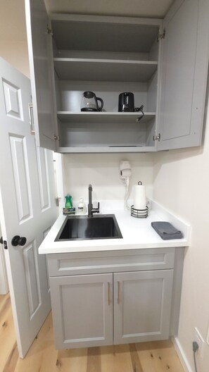 A compact kitchen with a sink, a coffee maker, and a hairdryer on the countertop. - Private Patio Studio + Desk & TV near SAP Center (San Jose)