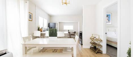 A modern, well-lit living space with a dining area, kitchen, and a bedroom.