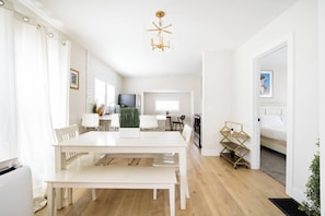 A modern, well-lit living space with a dining area, kitchen, and a bedroom. - Beds for Ten, Bathrooms for a Family • 4BR (Portland)