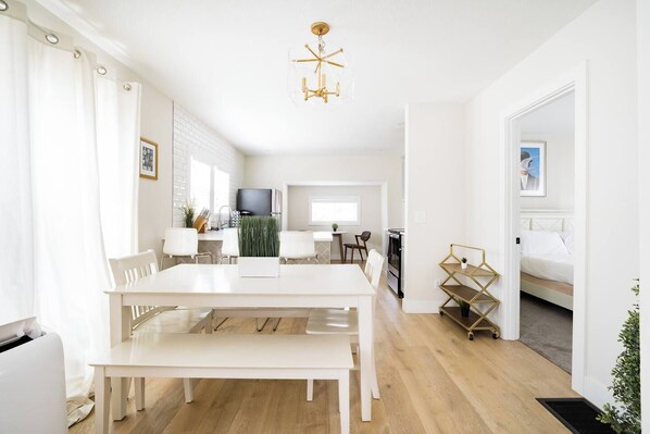 Un espacio de estar moderno y bien iluminado con comedor, cocina y un dormitorio.