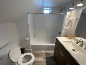 A modern bathroom with a toilet, bathtub, and vanity. - Beds for Ten, Bathrooms for a Family • 4BR (Portland)