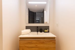 A bathroom with a white sink, a black faucet, and a mirror above it. - New Listing (anse marcel)