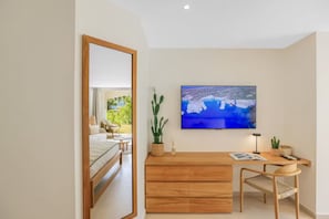 Un dormitorio moderno con una cama, un escritorio, una silla, un televisor y un ventanal grande.