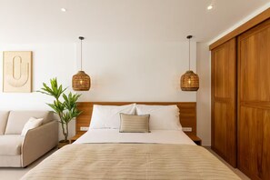 A hotel room with a bed, a bedside table, a lamp, a plant, and a wardrobe. - New Listing (anse marcel)