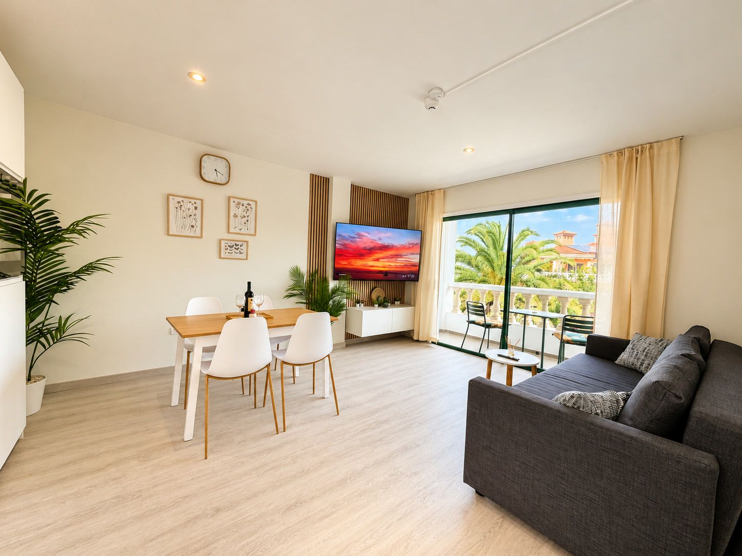 Een moderne woonkamer met een bank, eettafel, stoelen, een televisie en een balkon met uitzicht.