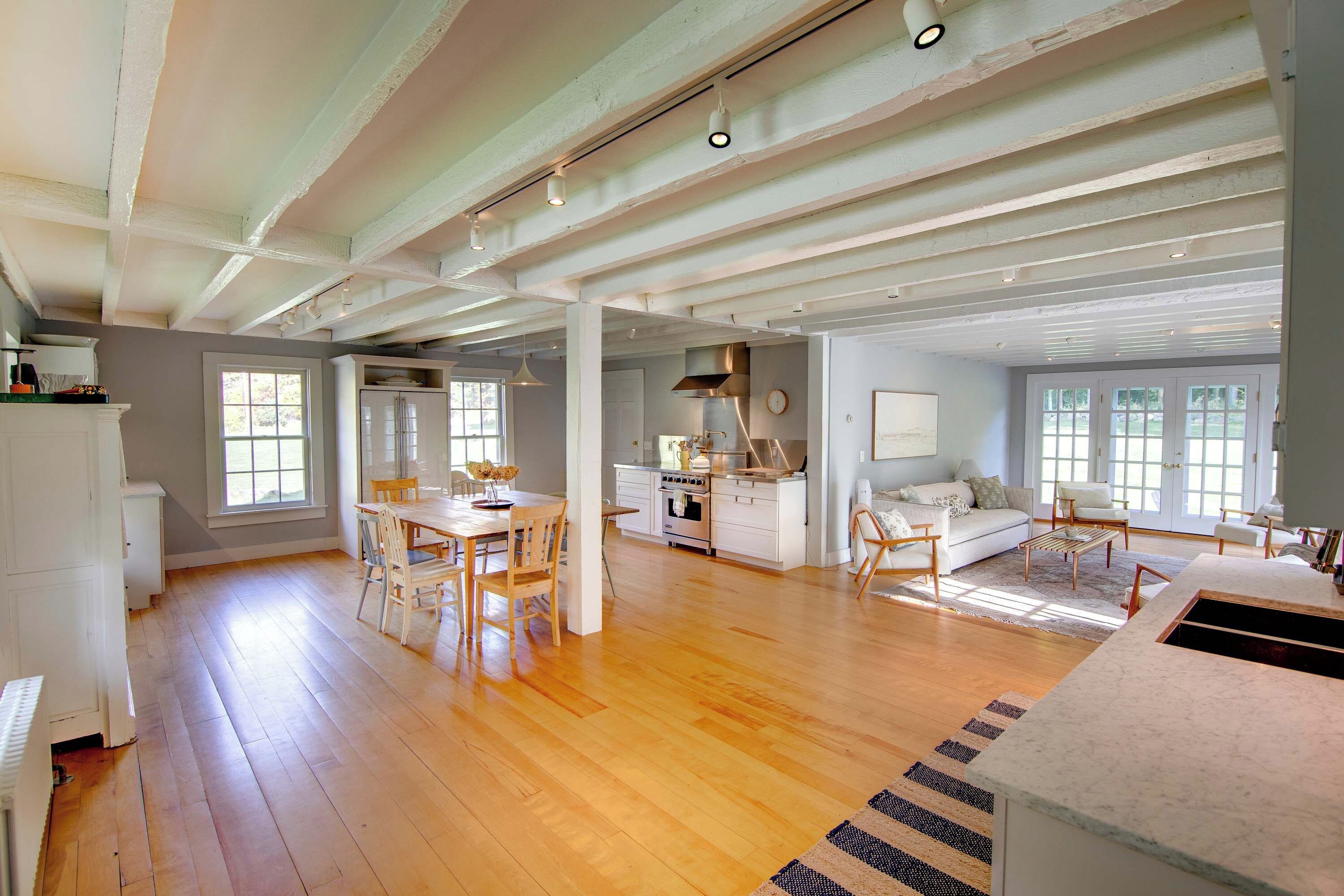 Un espacio habitable amplio con piso de madera, una mesa de comedor con sillas, una cocina con electrodomésticos modernos y un ventanal que proporciona luz natural.