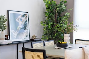 A dining area with a table, chairs, a potted plant, a framed picture, and a vase with flowers. - Luxurious Westside Townhome with Views and Parking (Los Angeles)