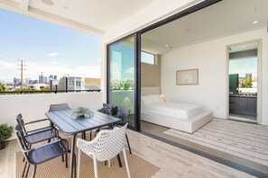 A modern apartment with a balcony, a dining area, a bed, and a view of the city skyline. - Luxurious Westside Townhome with Views and Parking (Los Angeles)