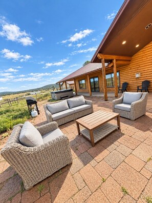 A log cabin with outdoor seating, including a sofa and chairs, and a hot tub. - Mountain Meadow Ranch Private 5-Acre Escape (Parks)