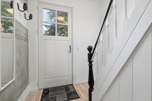 A white door with a window, a black balustrade, and a patterned doormat.