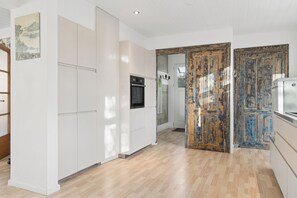 A modern kitchen with white cabinetry, a built-in oven, and a wooden floor.