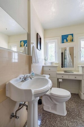 A bathroom with a pedestal sink, toilet, and a mirror above the sink.