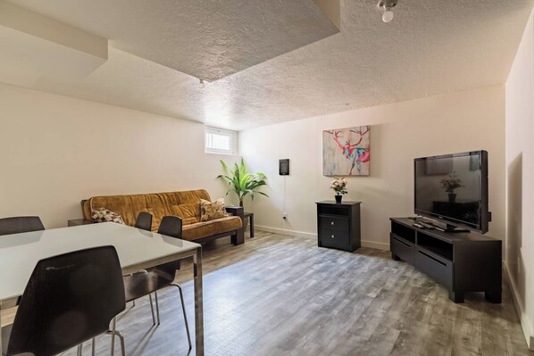 Sala de estar com sofá, televisão e mesa de jantar com cadeiras.