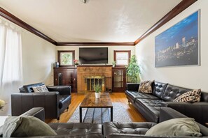 A living room with a fireplace, leather sofas, a coffee table, and a flat-screen TV.