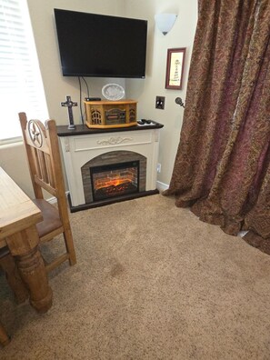 A room with a fireplace, a television mounted on the wall, and a patterned curtain. - 2-bedroom b&b, Woodland Park, COLORADO with views of Pikes Peak/the 
Rockies (Woodland Park)