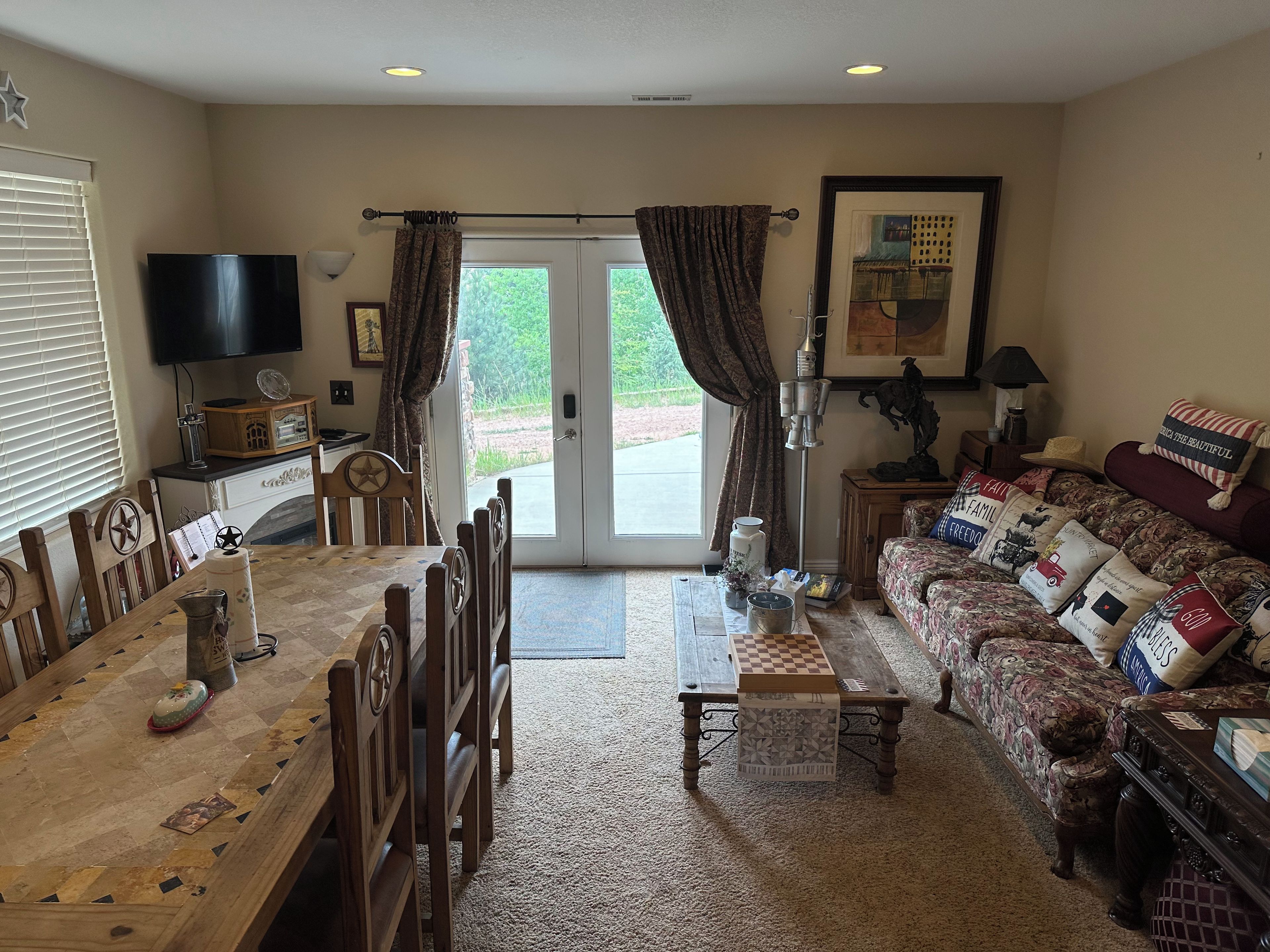 A living room with a dining area, a sofa with decorative pillows, a television, and a fireplace.