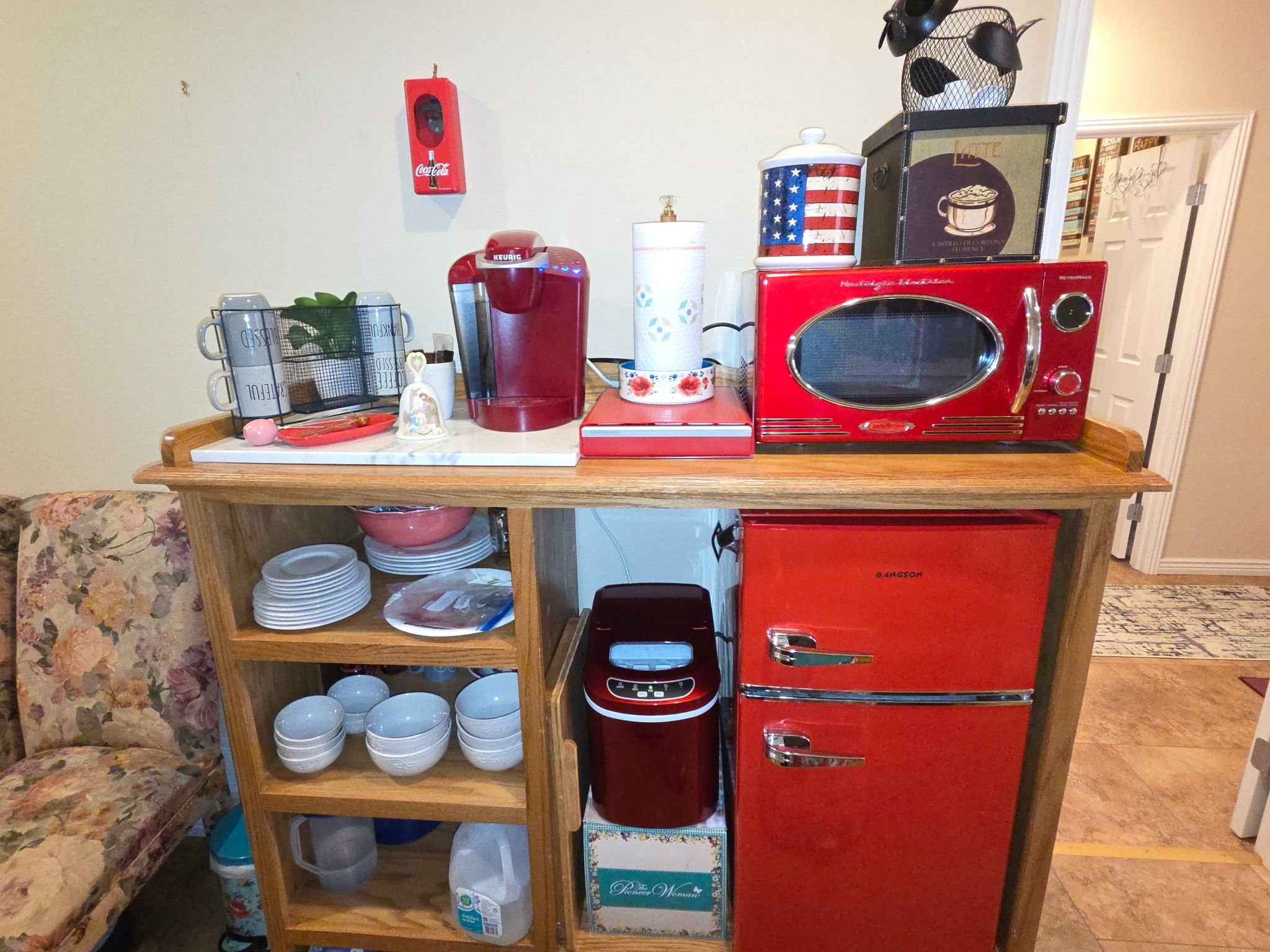 Eine Küchenzeile mit einem roten Kühlschrank, einer Mikrowelle, einer Kaffeemaschine und einem Spülbecken.