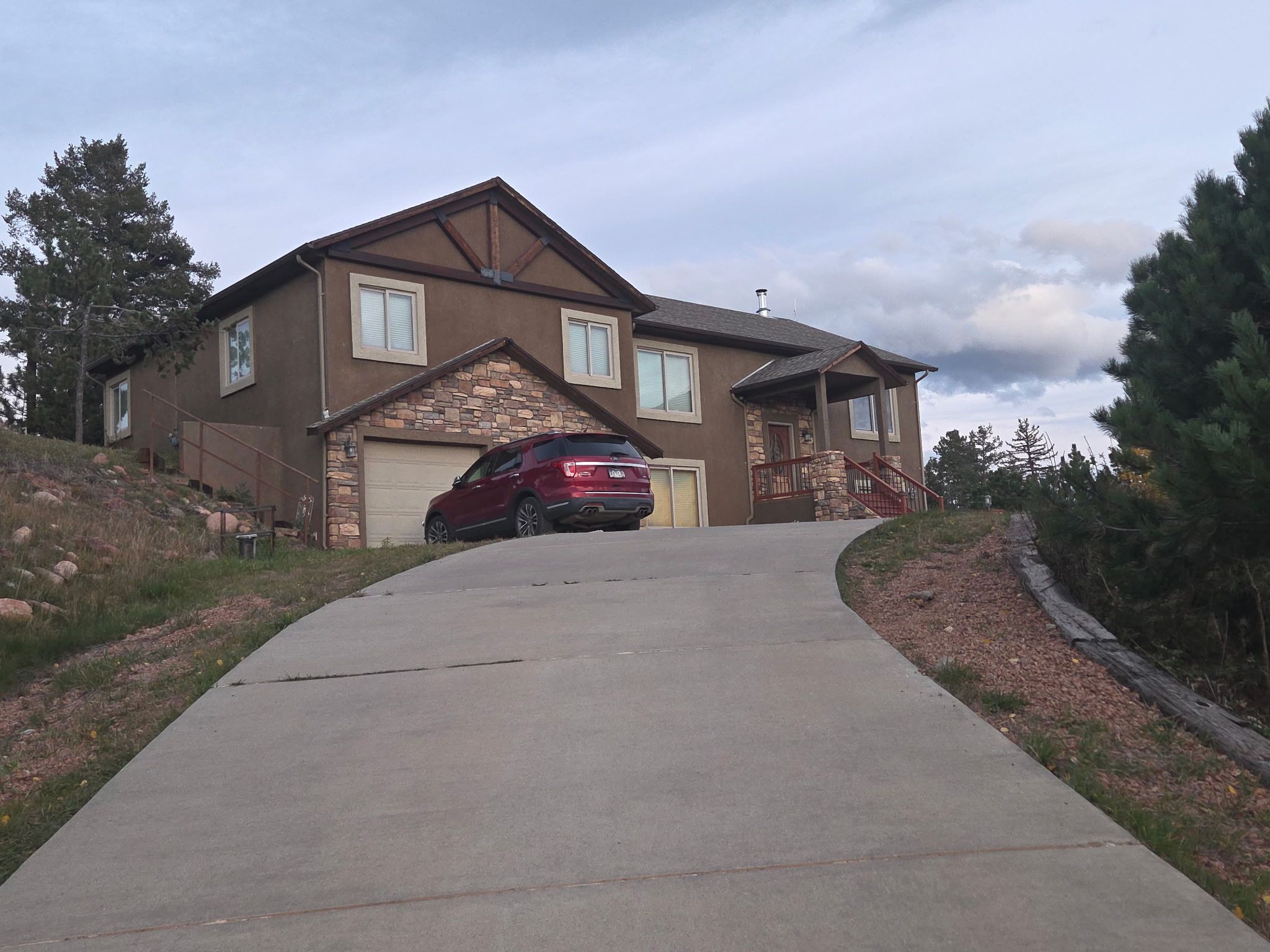 A two-story house with a stone facade, a garage, and a driveway leading to the front door.