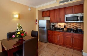 A compact kitchen with wooden cabinets, a stainless steel refrigerator, a microwave, and a tiled backsplash. - Studio @ Divi Village -Infinity Pool! (Oranjestad)