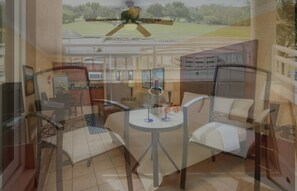A room with a bed, a small table, and a chair. There is a window with a view of a green landscape. - Studio @ Divi Village -Infinity Pool! (Oranjestad)