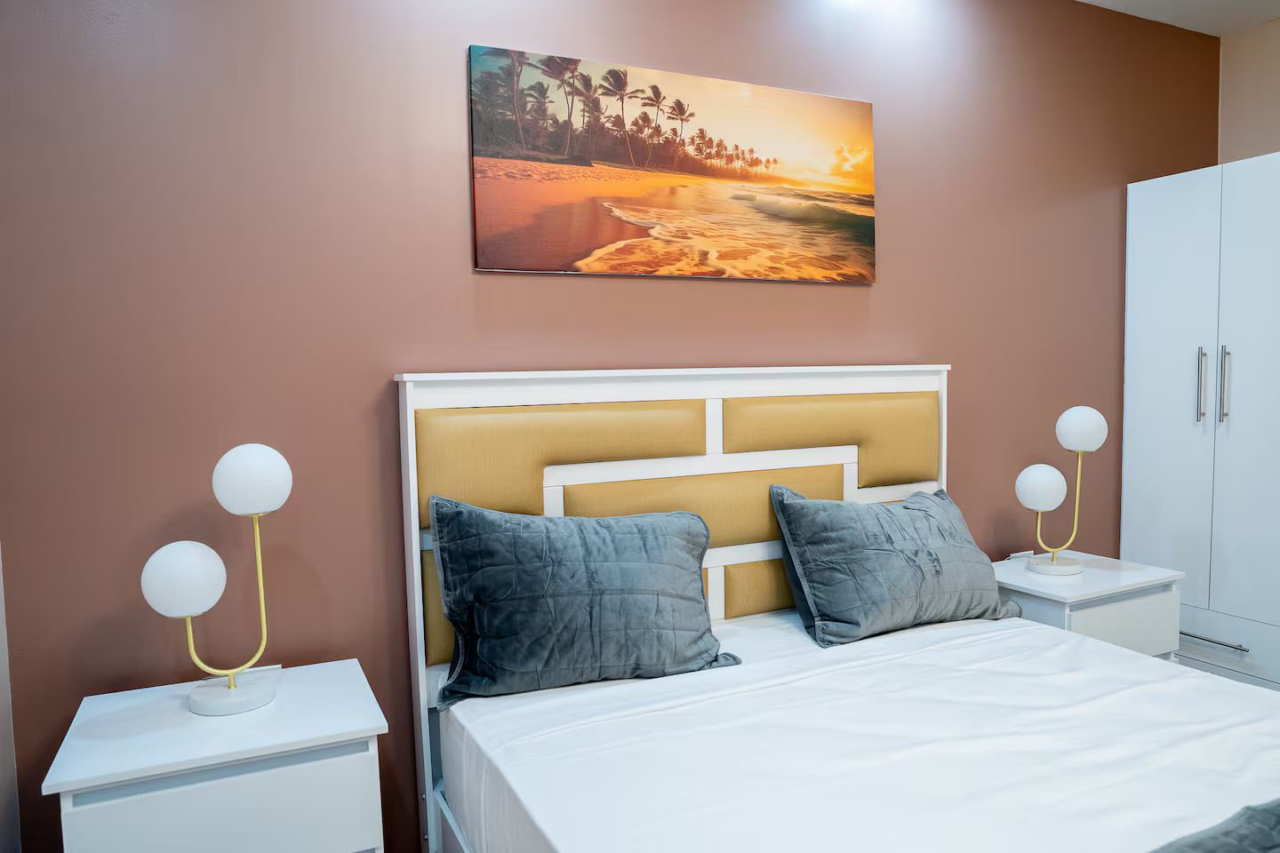 Ein Schlafzimmer mit einem Bett, zwei Nachttischen, einem Wandbild und einem Kleiderschrank.
