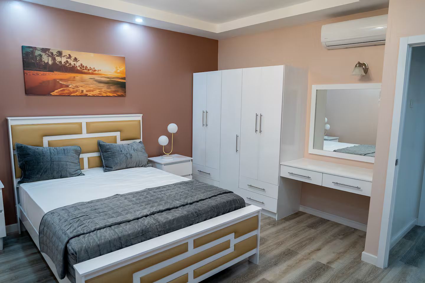 Ein Schlafzimmer mit einem Bett, Nachttischen, einem Kleiderschrank und einem Spiegel.