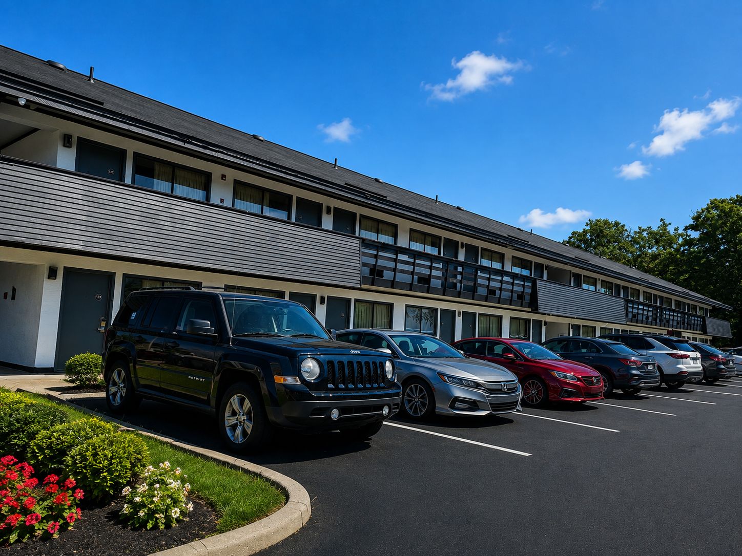 A parking lot with multiple cars, a building with a flat roof, and a clear sky.