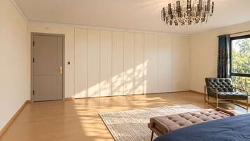 A bedroom with a large bed, a chair, a wardrobe, and a chandelier.