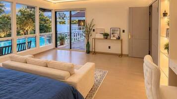 Un dormitorio moderno con una cama grande, un espacio de descanso y vistas a una piscina.
