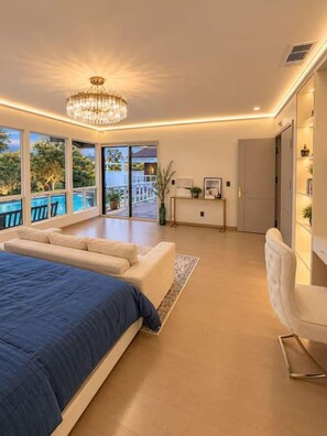 Une chambre moderne dotée d’un grand lit, d’un coin salon et offrant une vue sur une piscine.
