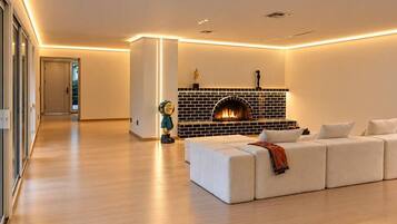 Una sala moderna con chimenea, un sofá blanco y piso de madera.