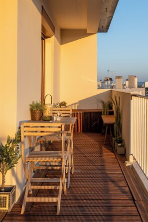 A wooden deck with a table and chairs, potted plants, and a view of the cityscape. - New Listing (Tinqueux)