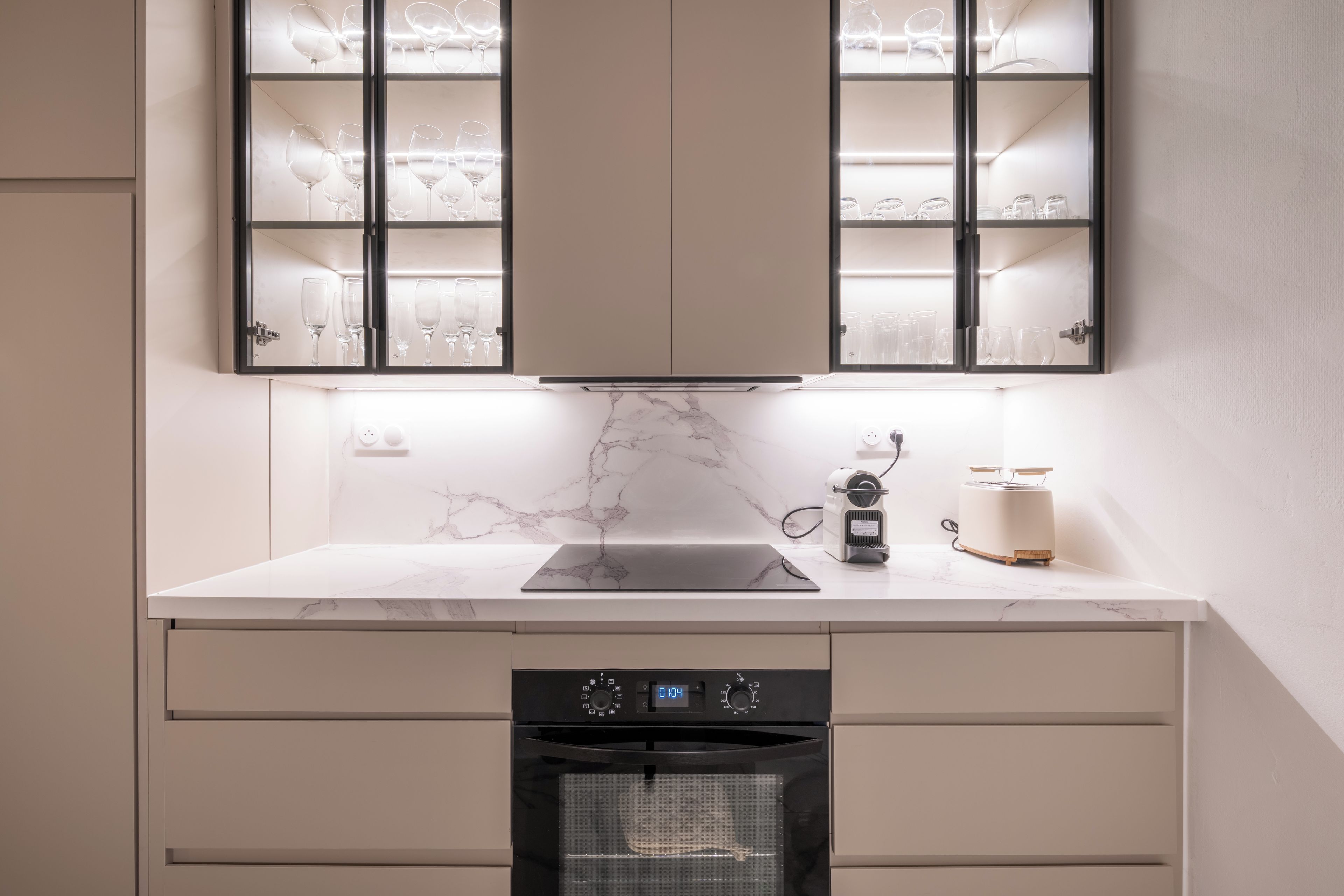 Une cuisine équipée d’un four encastré, d’un plan de travail avec un grille-pain et d’un meuble contenant des verres à vin.