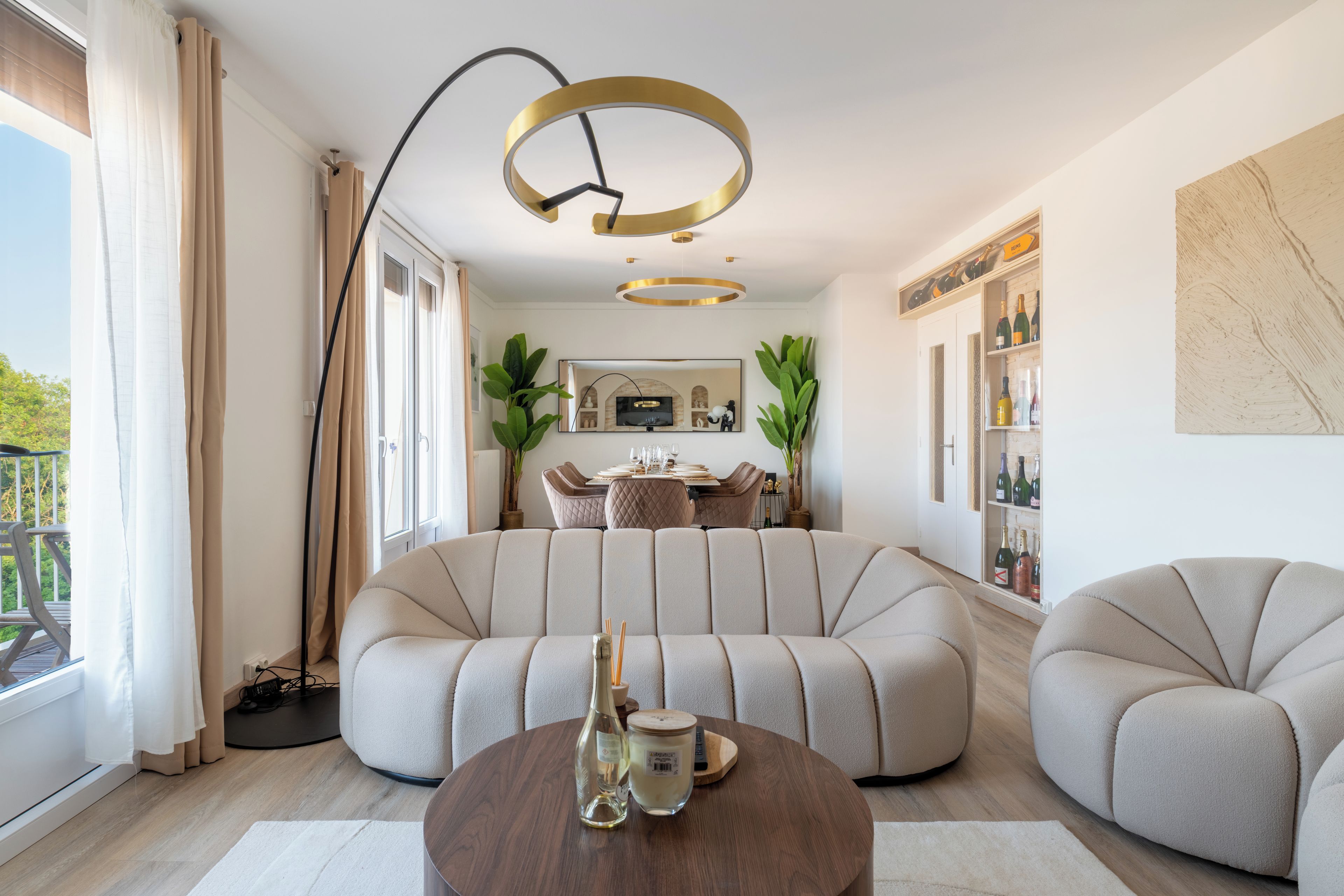 Un salon moderne avec un canapé d’angle, une table basse ronde et un coin repas comprenant une table et des chaises.
