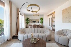 Ein modernes Wohnzimmer mit einer Eckcouch, einem runden Couchtisch und einem Essbereich mit Tisch und Stühlen.