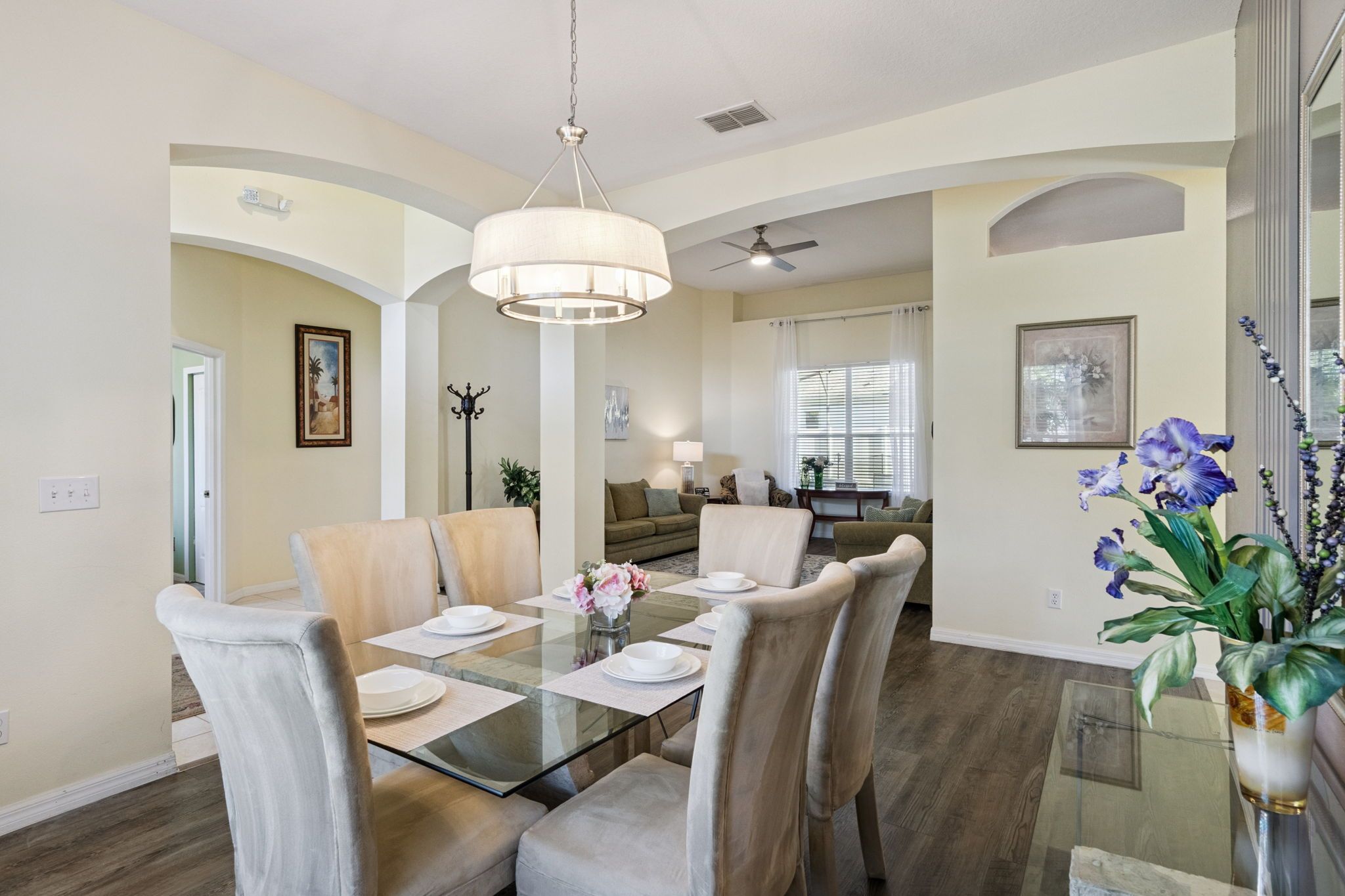 A dining area with a glass table, chairs, and a vase of flowers.