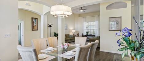 A dining area with a glass table, chairs, and a vase of flowers.