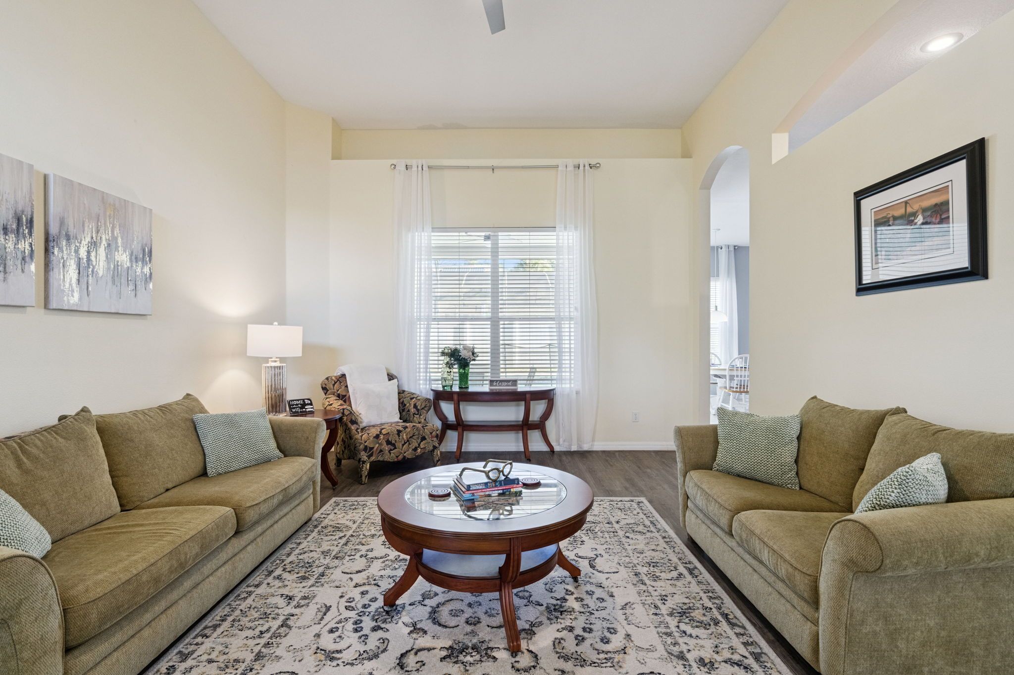 A living room with two sofas, a coffee table, a lamp, and a window with curtains.