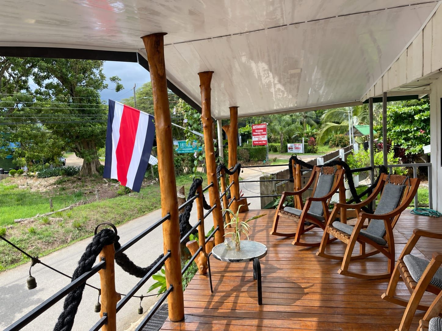 A covered outdoor seating area with wooden chairs and a flag.