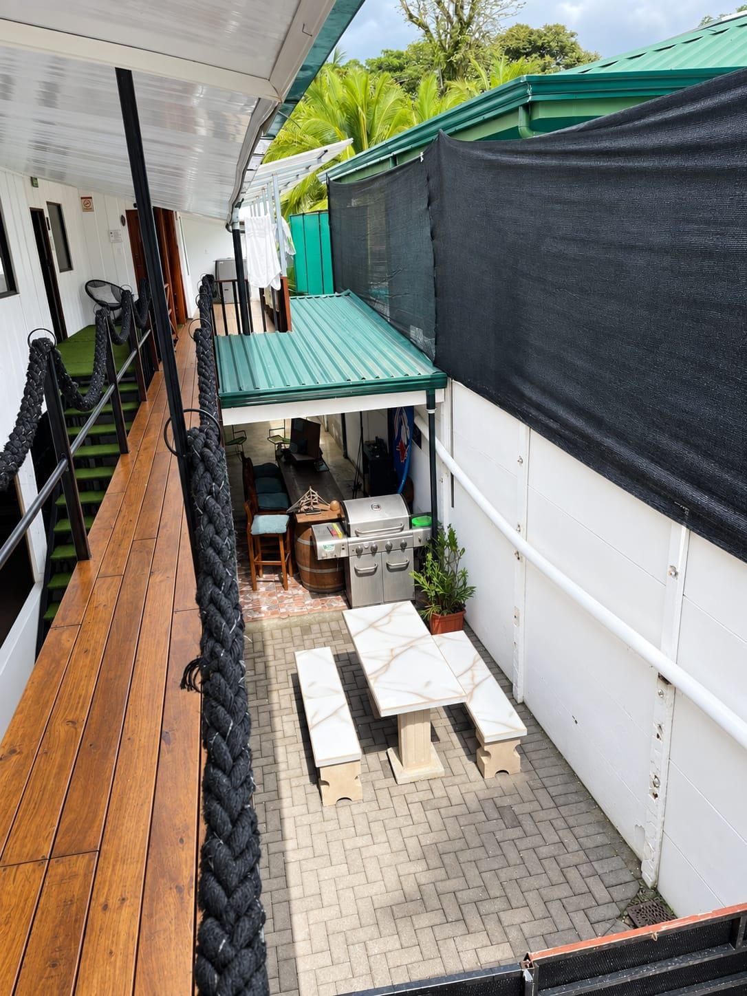 A covered outdoor area with a barbecue grill, wooden tables, and a rope barrier.