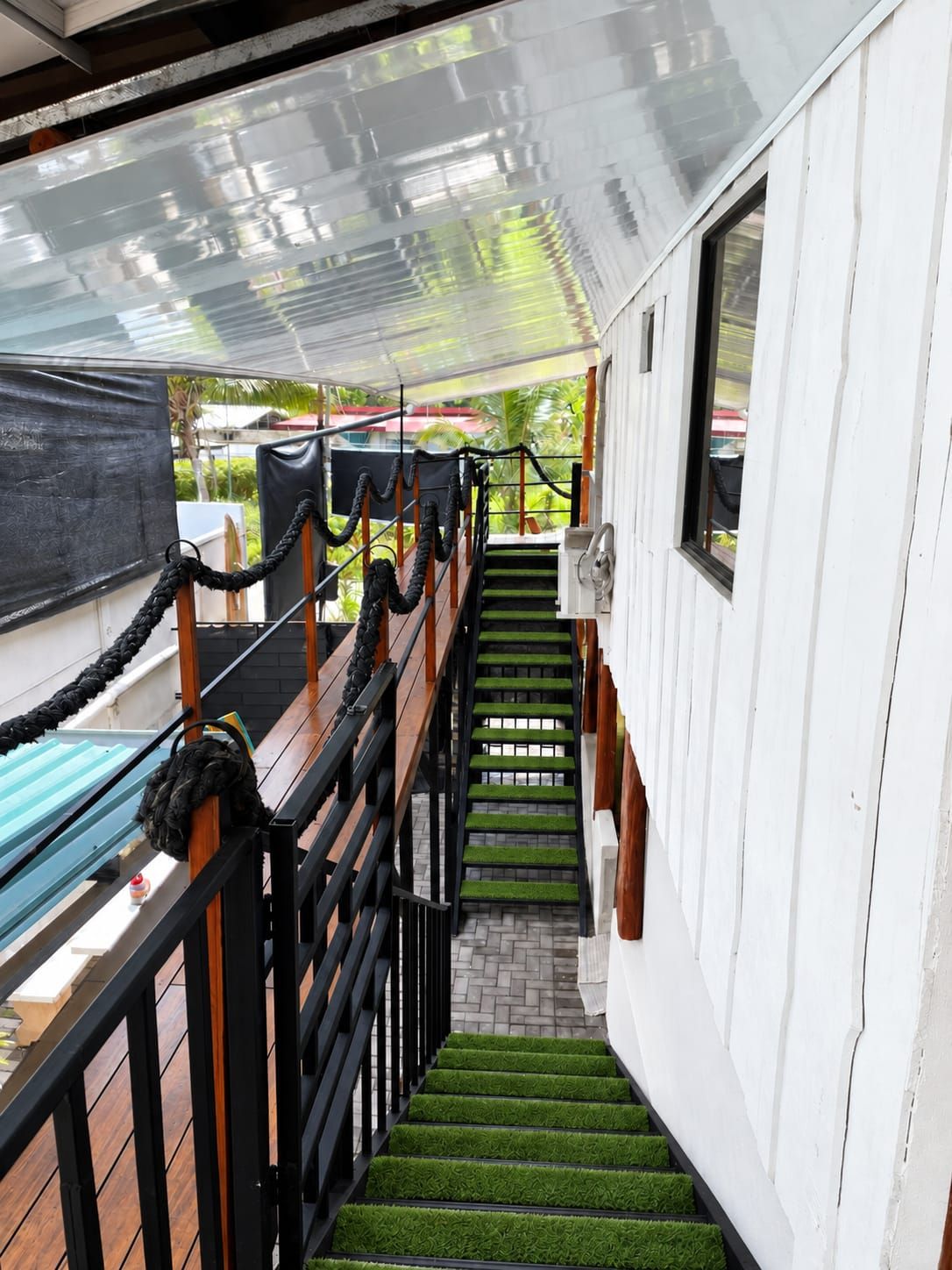 Una escalera con peldaños cubiertos de césped artificial sintético que conduce a un espacio exterior techado con una piscina.