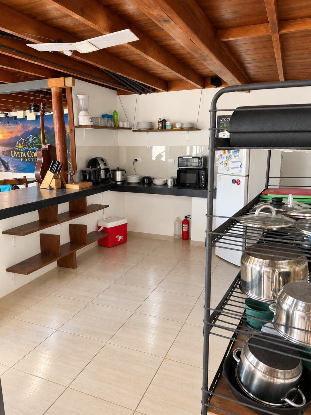 A kitchen with wooden beams, a coffee machine, a microwave, and a red cooler.