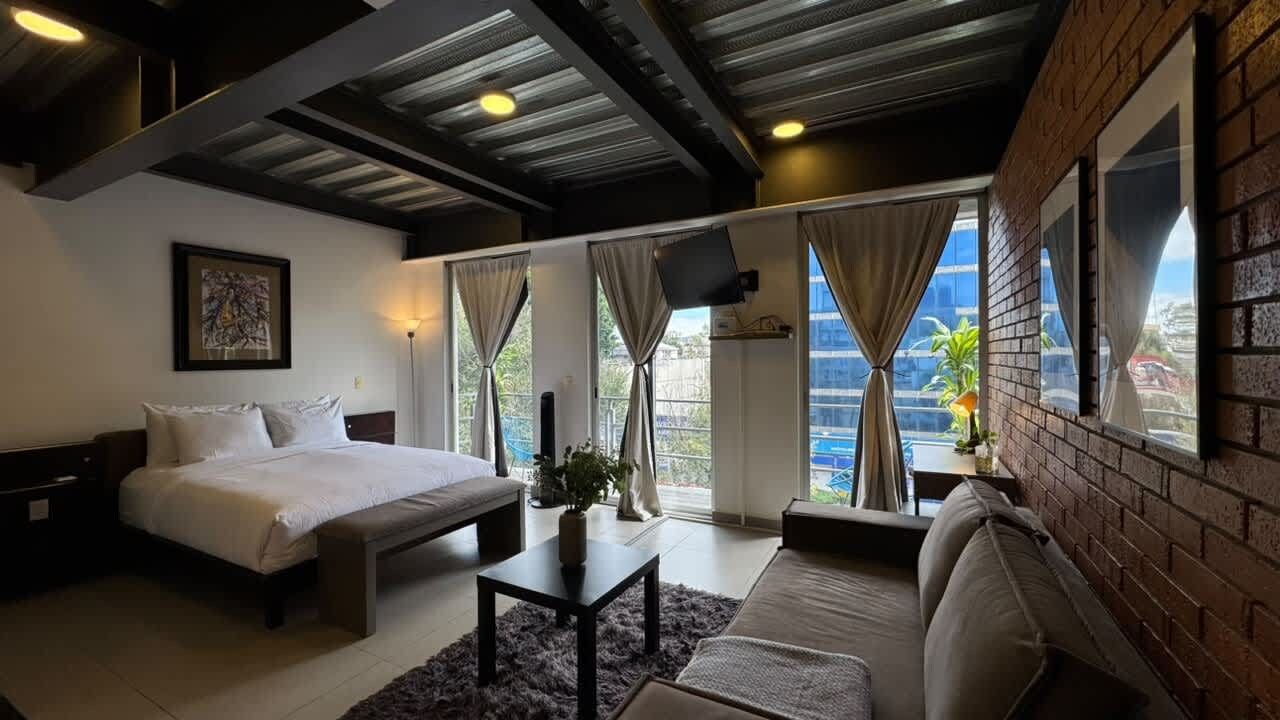 Een slaapkamer met een bed, een bank, een tafel en een televisie.