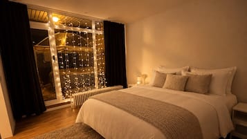 Ein Schlafzimmer mit einem großen Bett, einem Heizkörper, einem Nachttisch und einem Fenster mit Vorhängen.