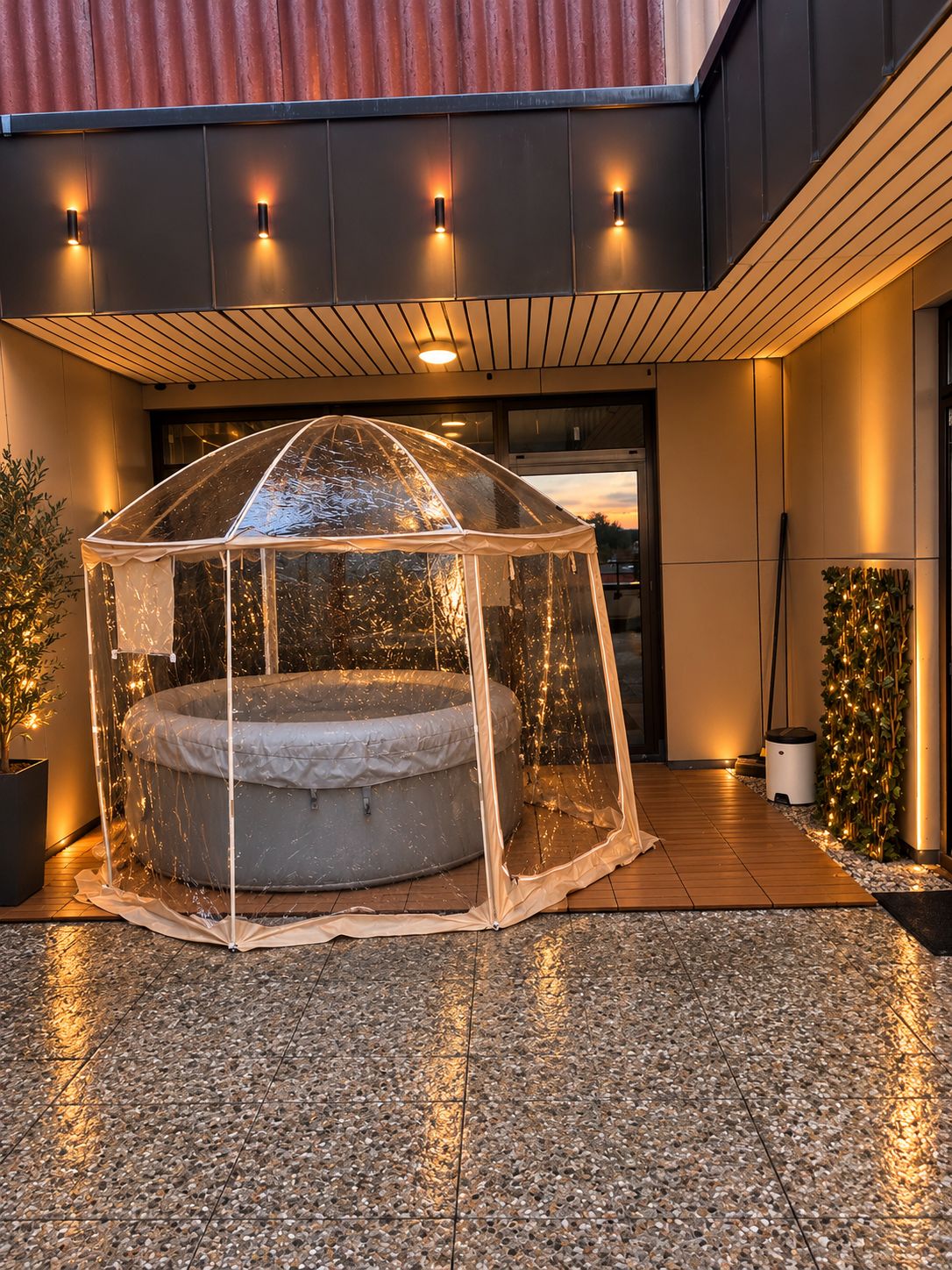 Ein durchsichtiges Pavillon mit Whirlpool darunter, umgeben von einer gefliesten Terrasse.